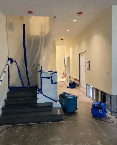 Plastic containment and air movers in a water-damaged stairwell and hall